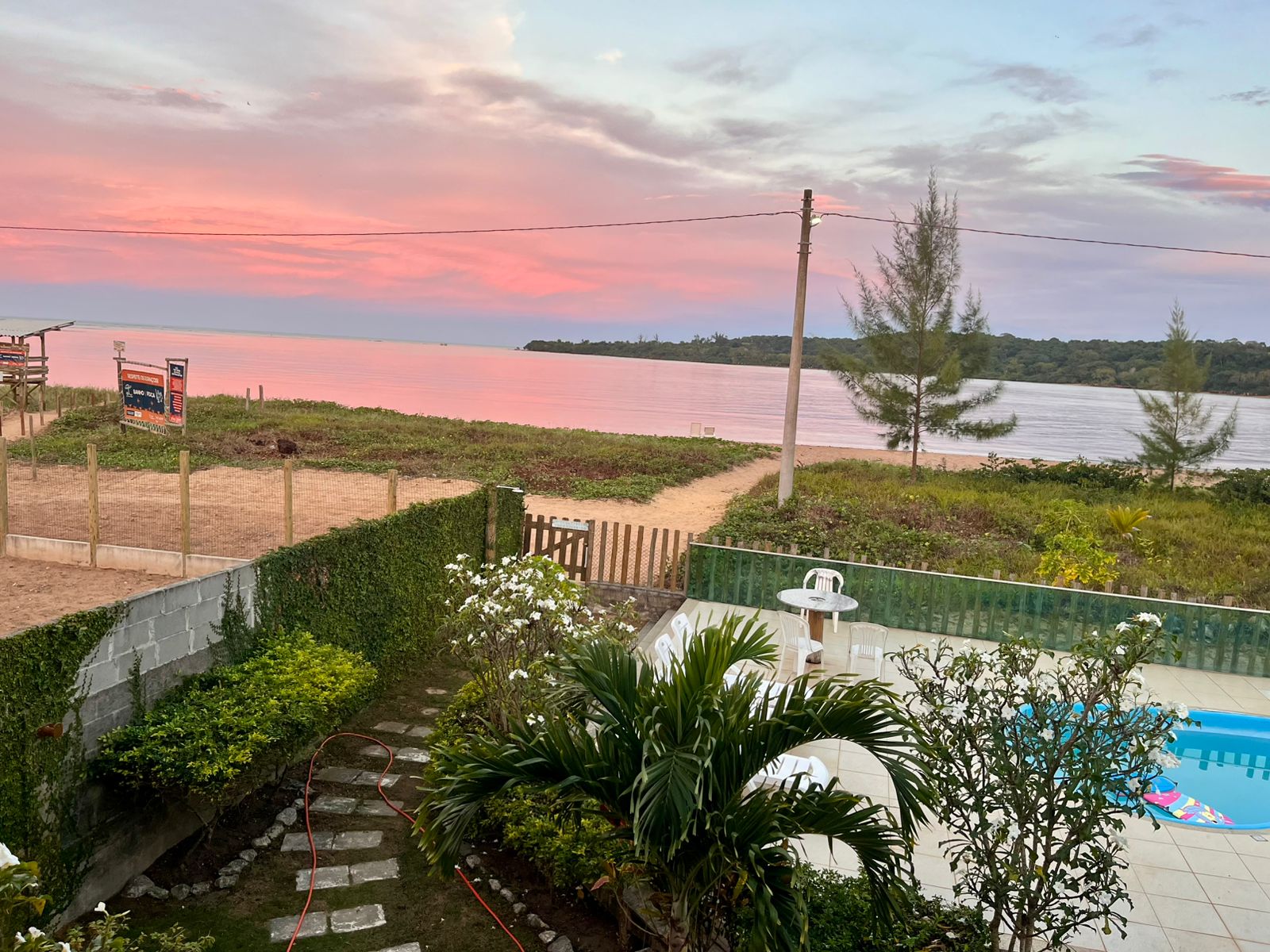 Piscina da pousada com vista do rio ao entardecer rosado