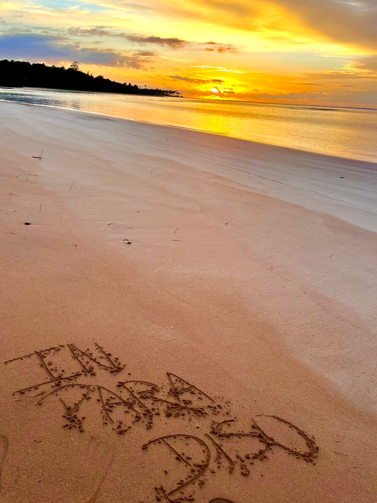 In Paradiso escrito na areia ao pôr do sol